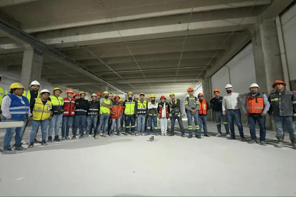 Personal de [NOMBRE EMPRESA] reunido en un espacio de obra antes de la jornada.